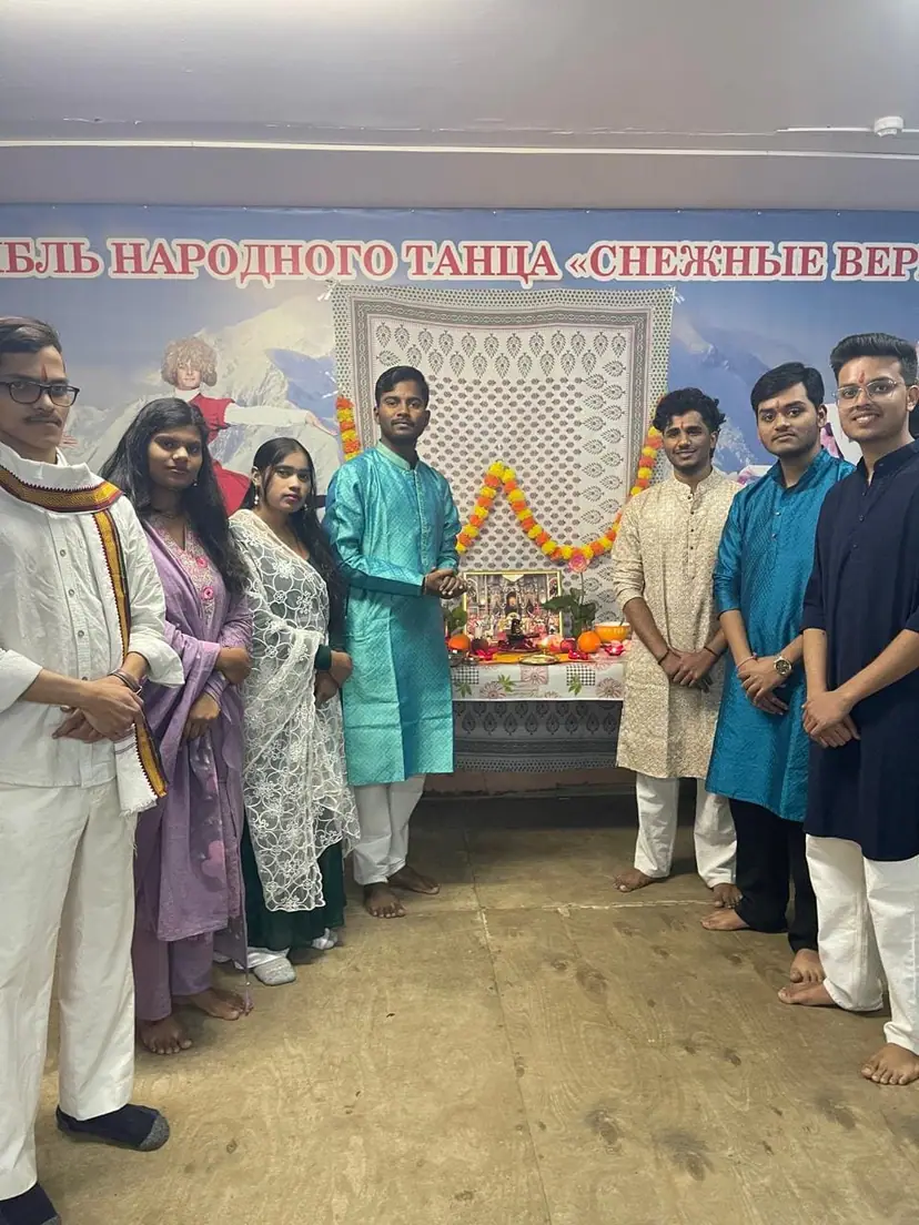 Indian students in traditional dress beside a decorated shrine during a festival at North Caucasian State Academy