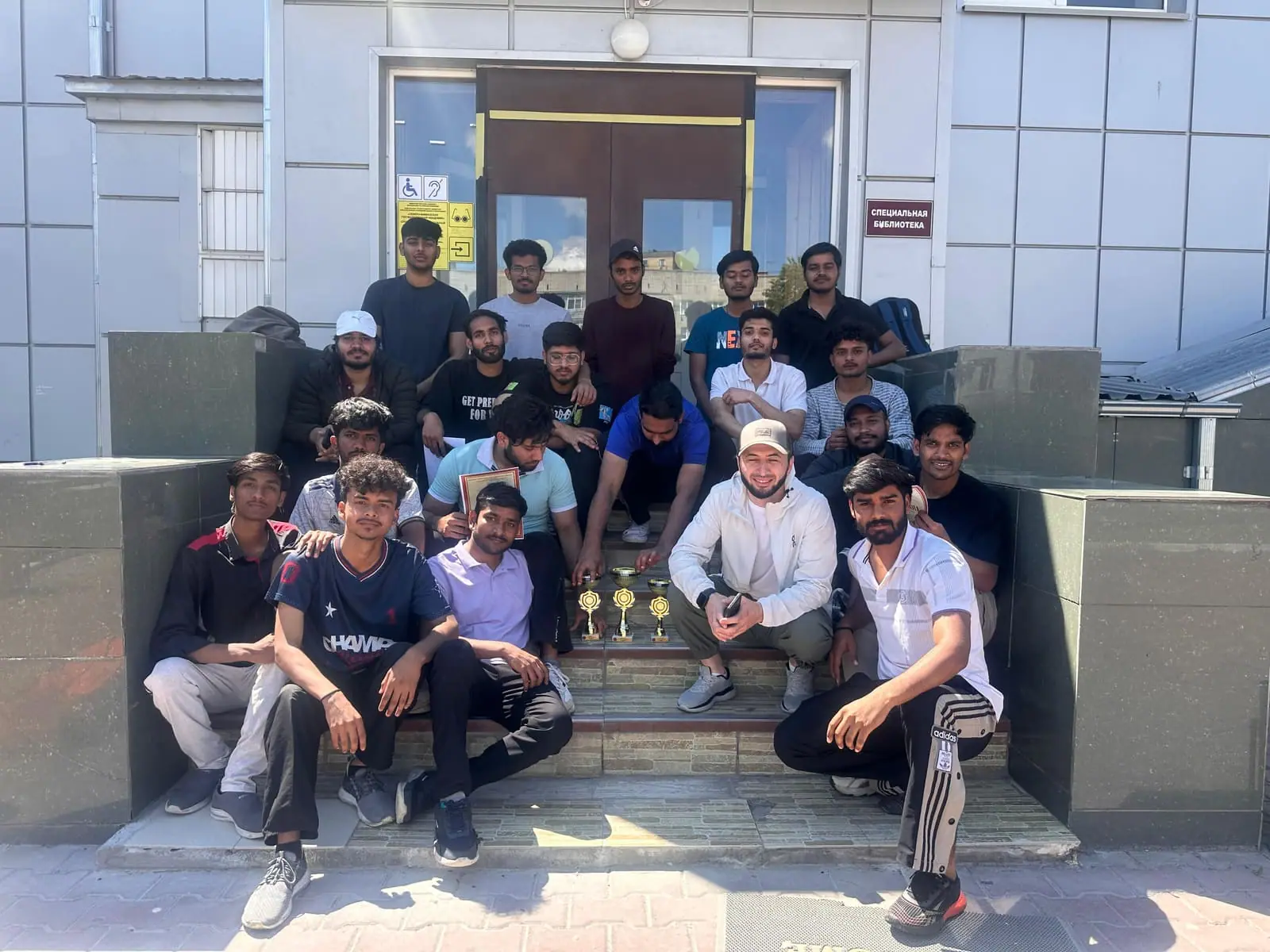 A large group of Indian medical students on the steps of the sports complex at North Caucasian State Academy with tournament trophies